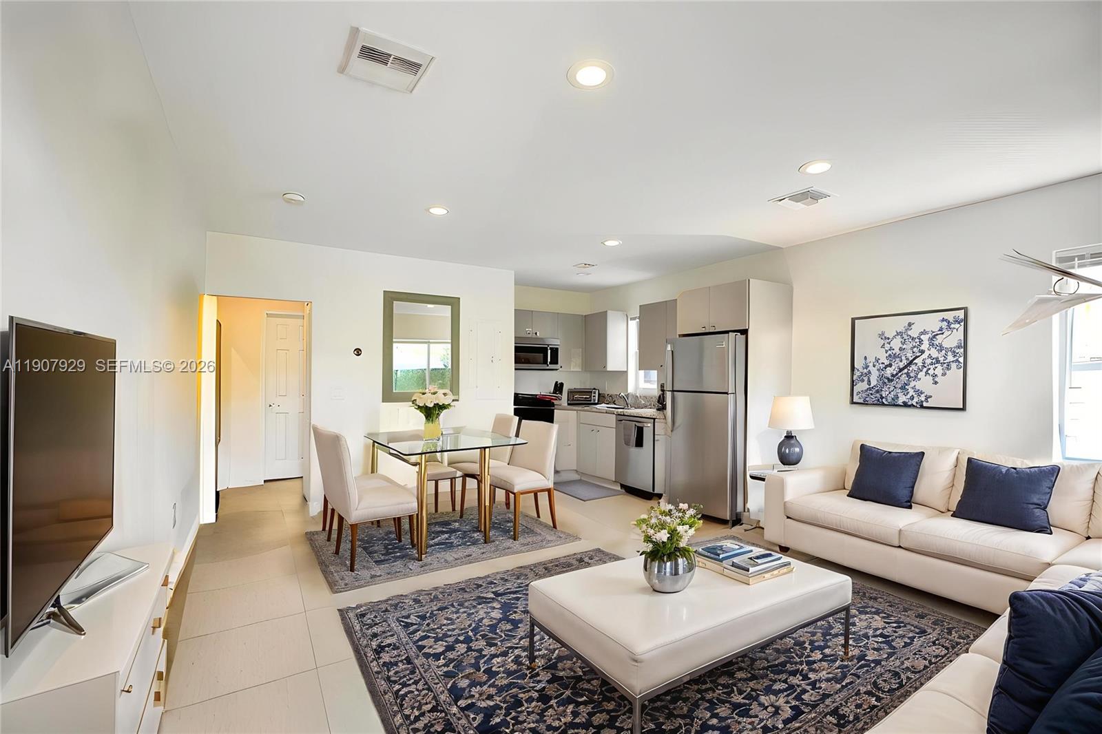 An open-concept living and dining area features a kitchen, tile flooring, and neutral furniture — 322 Oklahoma St, Hollywood FL 33019, HOLLYWOOD, FL