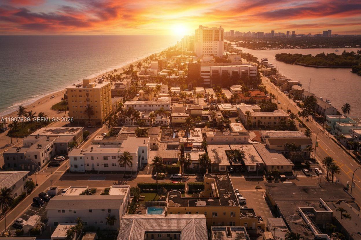 An aerial view shows a coastal neighborhood with buildings, a beach, and a sunset sky — 322 Oklahoma St, Hollywood FL 33019, HOLLYWOOD, FL