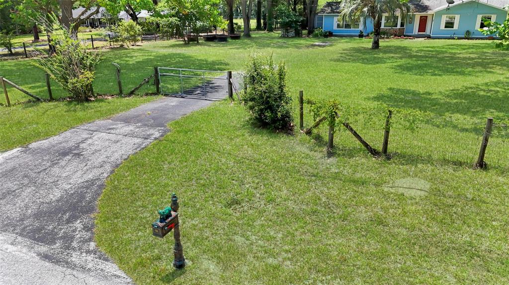 An aerial view shows a paved driveway leading to a metal gate on a grassy lot — 2800 SE 157TH LANE ROAD, SUMMERFIELD, FL