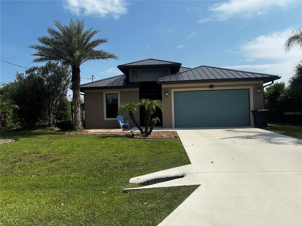A single-story house with a metal roof, a two-car garage, and a palm tree — 12 MAHOE DRIVE N, PALM COAST, FL