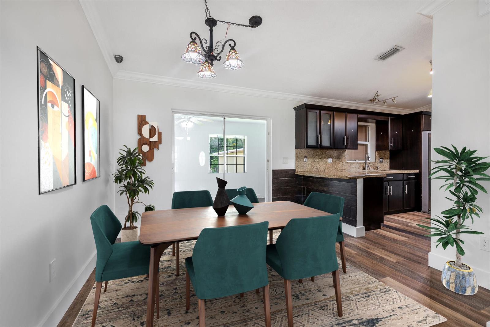 A dining room with a wooden table, teal chairs, and an adjacent open-concept kitchen — 15285 San Diego Drive, FL 33470, FL