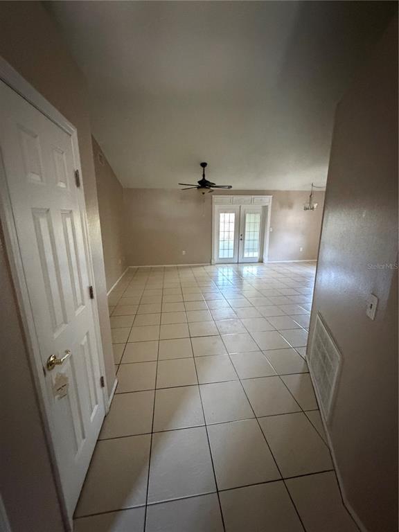 A tiled living area features a vaulted ceiling, a ceiling fan, and glass patio doors — 7119 PEBBLE PASS LOOP, LAKELAND, FL