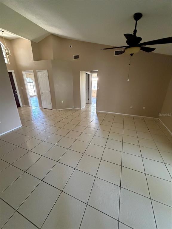 A spacious room with light-colored tile flooring, vaulted ceilings, and a ceiling fan — 7119 PEBBLE PASS LOOP, LAKELAND, FL