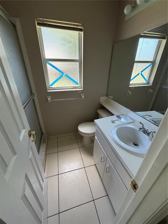 A small bathroom features a white vanity, a toilet, a shower stall, and a window — 7119 PEBBLE PASS LOOP, LAKELAND, FL