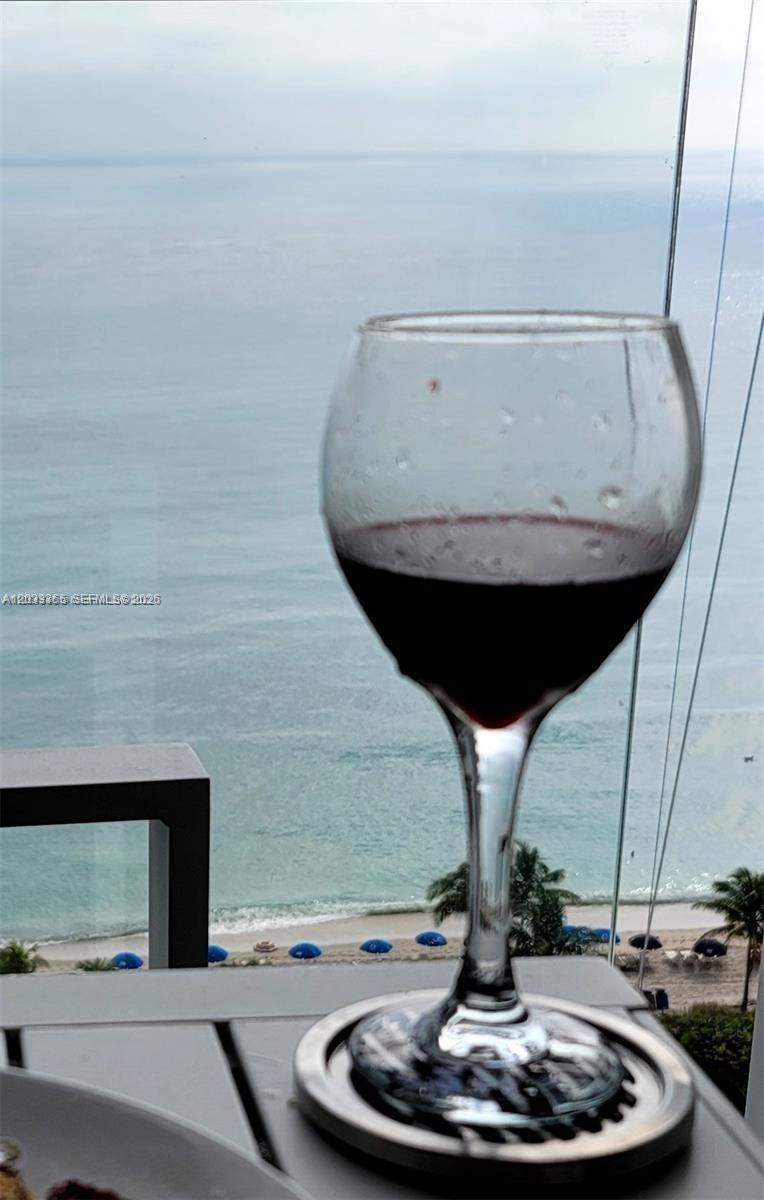 A glass of red wine sits on a balcony overlooking the ocean and beach — 2030 S Ocean Dr # 1815, Hallandale Beach FL 33009, HALLANDALE BEACH, FL