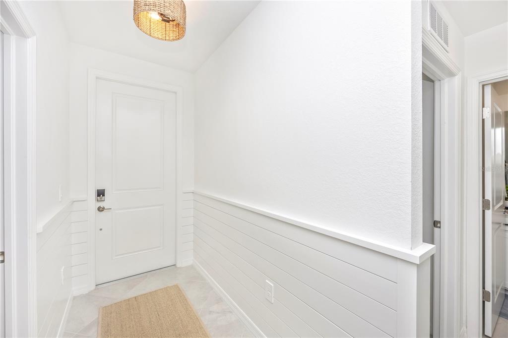 A bright entryway features white shiplap wainscoting, a woven light fixture, and a tiled floor — 17625 OPAL SAND DRIVE UNIT 106, VENICE, FL