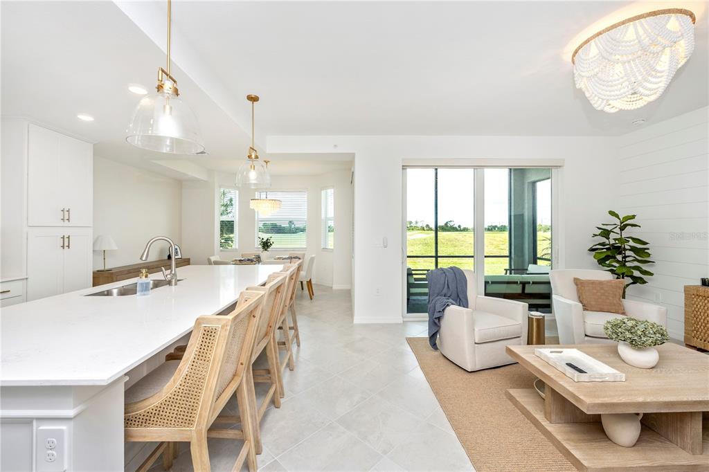 A bright open-concept kitchen and living area with a large island and sliding glass doors — 17625 OPAL SAND DRIVE UNIT 106, VENICE, FL