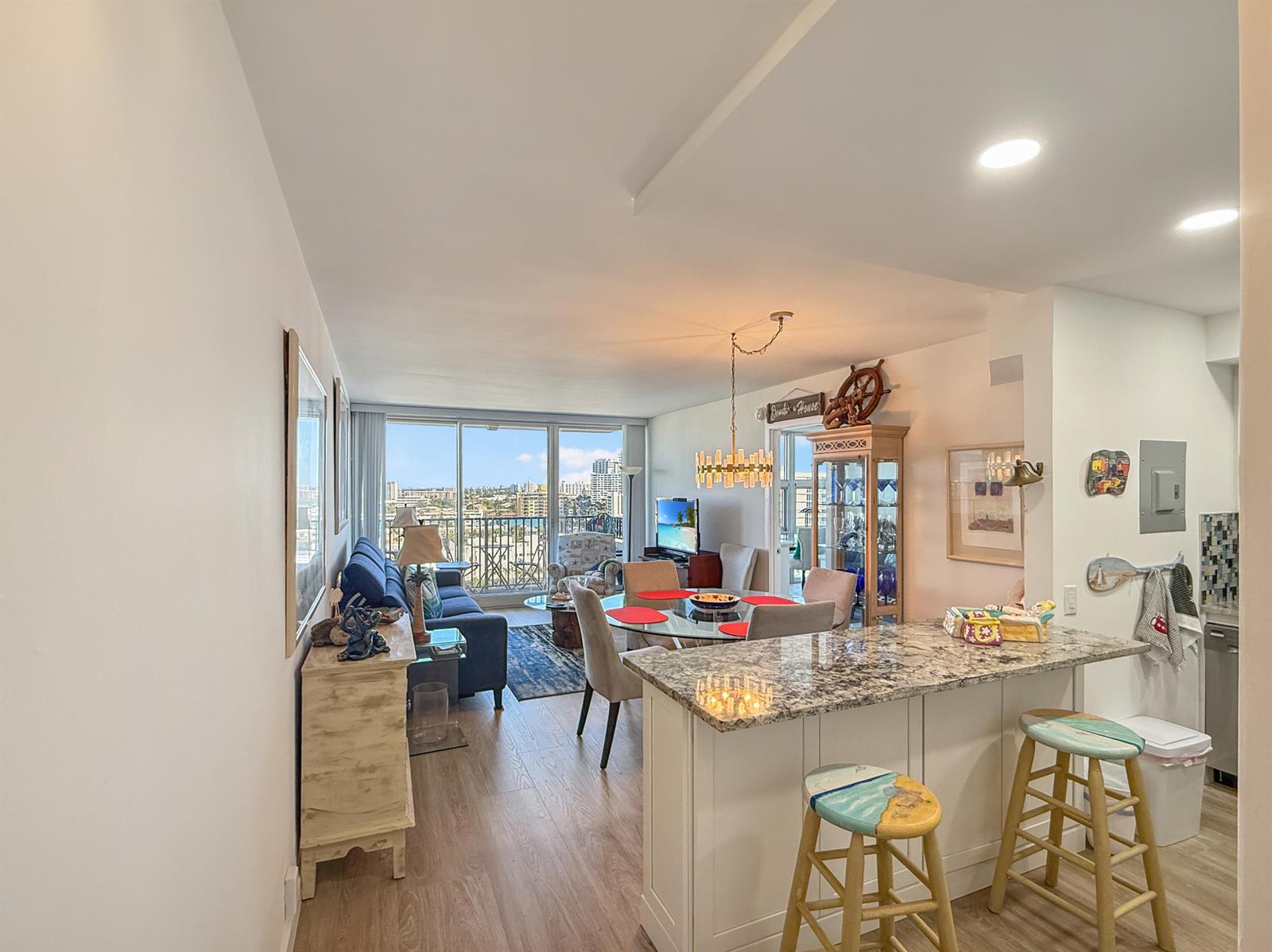An open-concept living and dining area features a kitchen island, hardwood floors, and balcony views — 531 N Ocean Boulevard # 1203, Pompano Beach FL 33062, POMPANO BEACH, FL