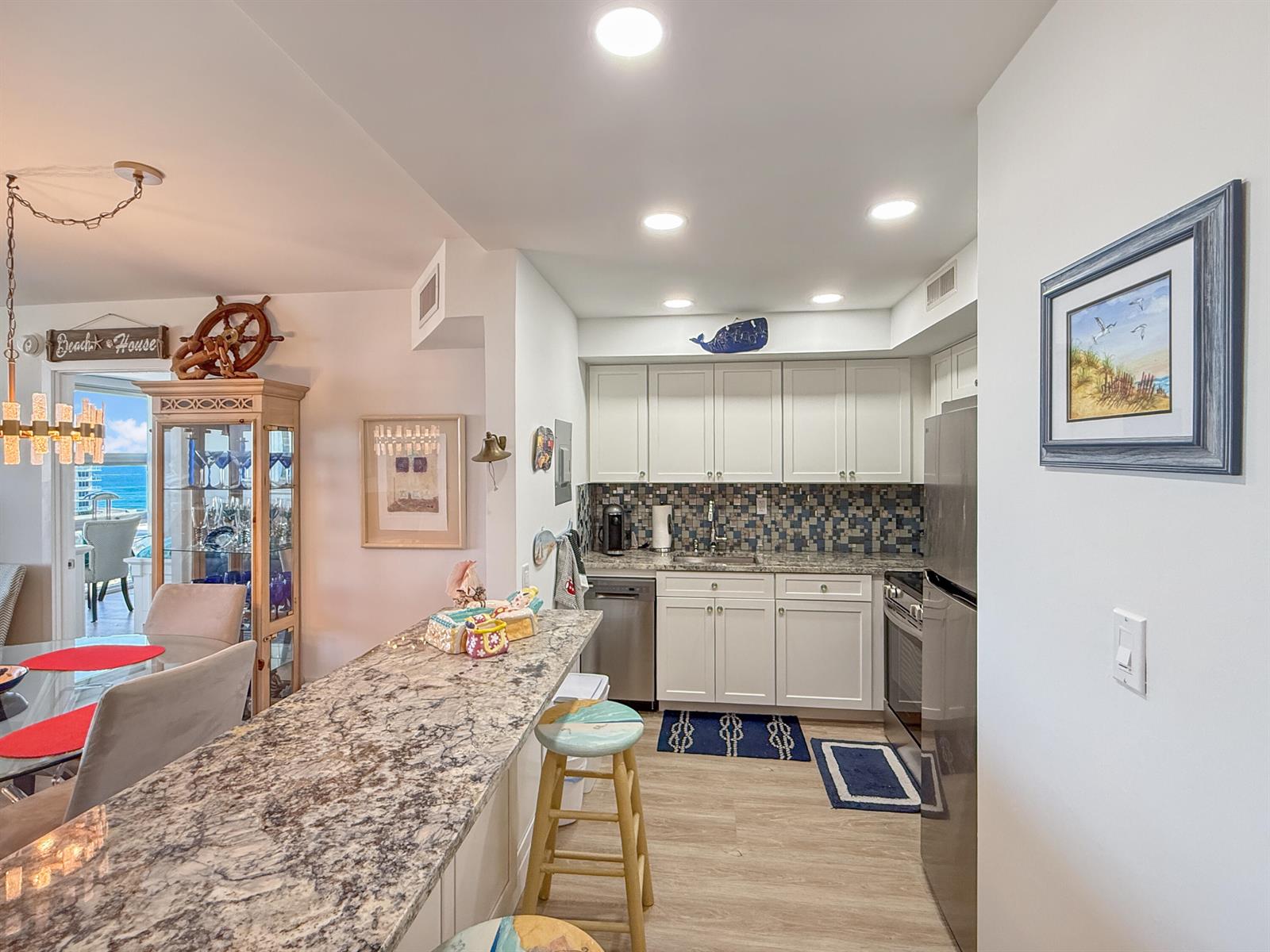 A kitchen features white cabinets, granite countertops, a mosaic backsplash, and a breakfast bar — 531 N Ocean Boulevard # 1203, Pompano Beach FL 33062, POMPANO BEACH, FL