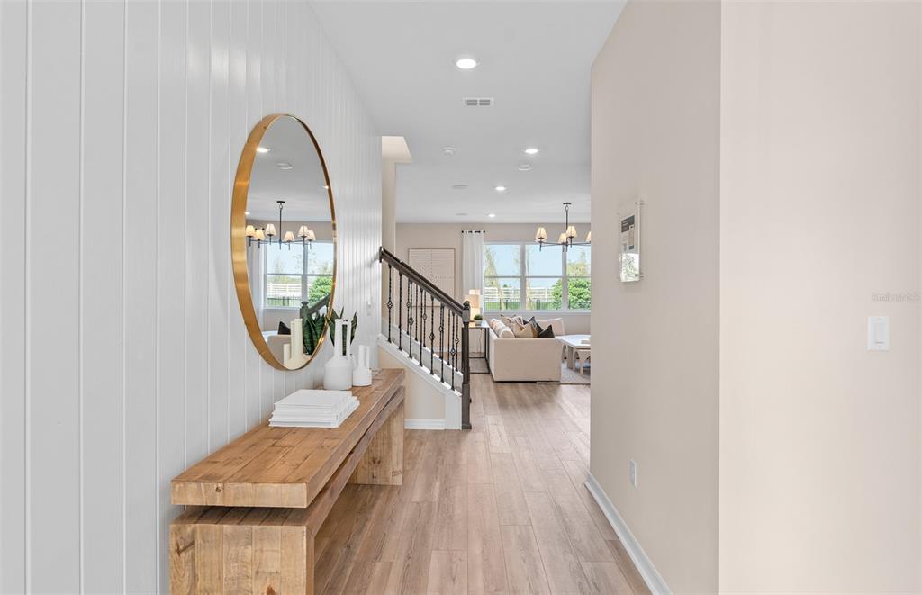 A bright entryway features wood-look flooring, a rustic console table, and a large oval mirror — 427 WINTER GROVE BOULEVARD, WINTER GARDEN, FL