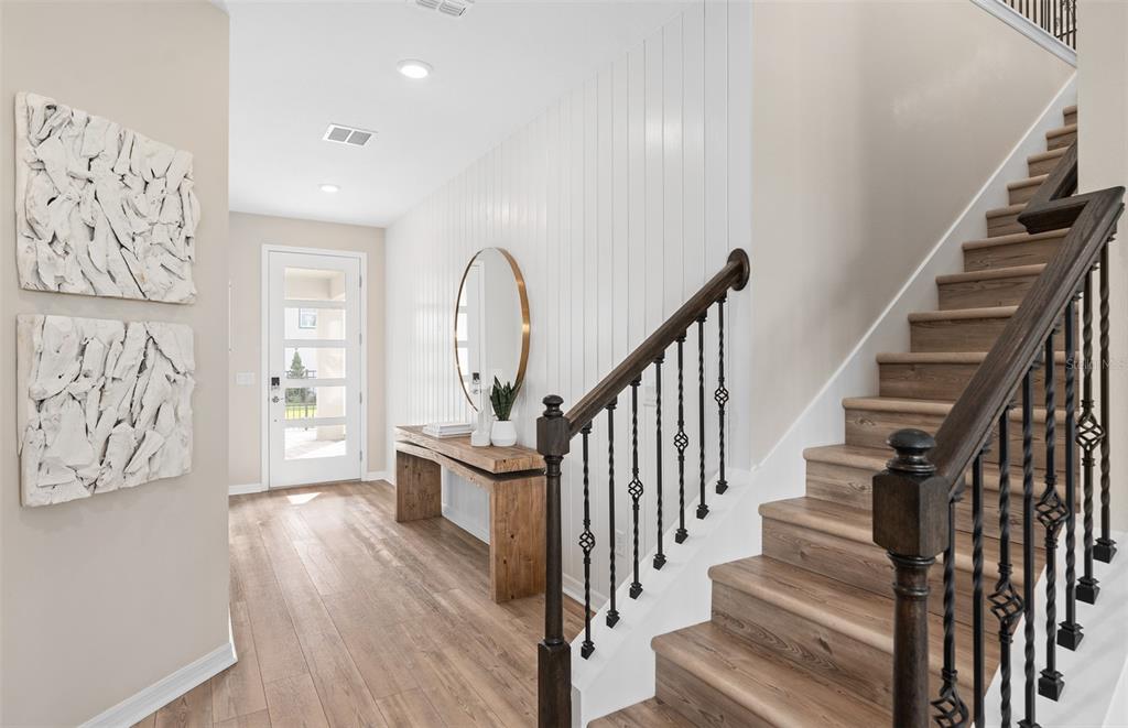 An entryway features wood-look flooring, a staircase with iron railings, and a white paneled wall — 427 WINTER GROVE BOULEVARD, WINTER GARDEN, FL