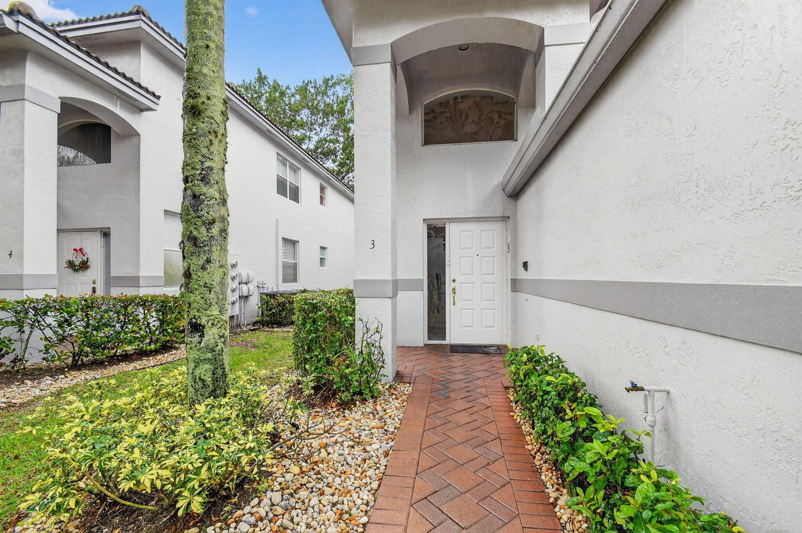 The exterior view shows a white building entrance with a brick walkway and landscaping — 7910 Laina Lane # 3, Boynton Beach FL 33437, BOYNTON BEACH, FL