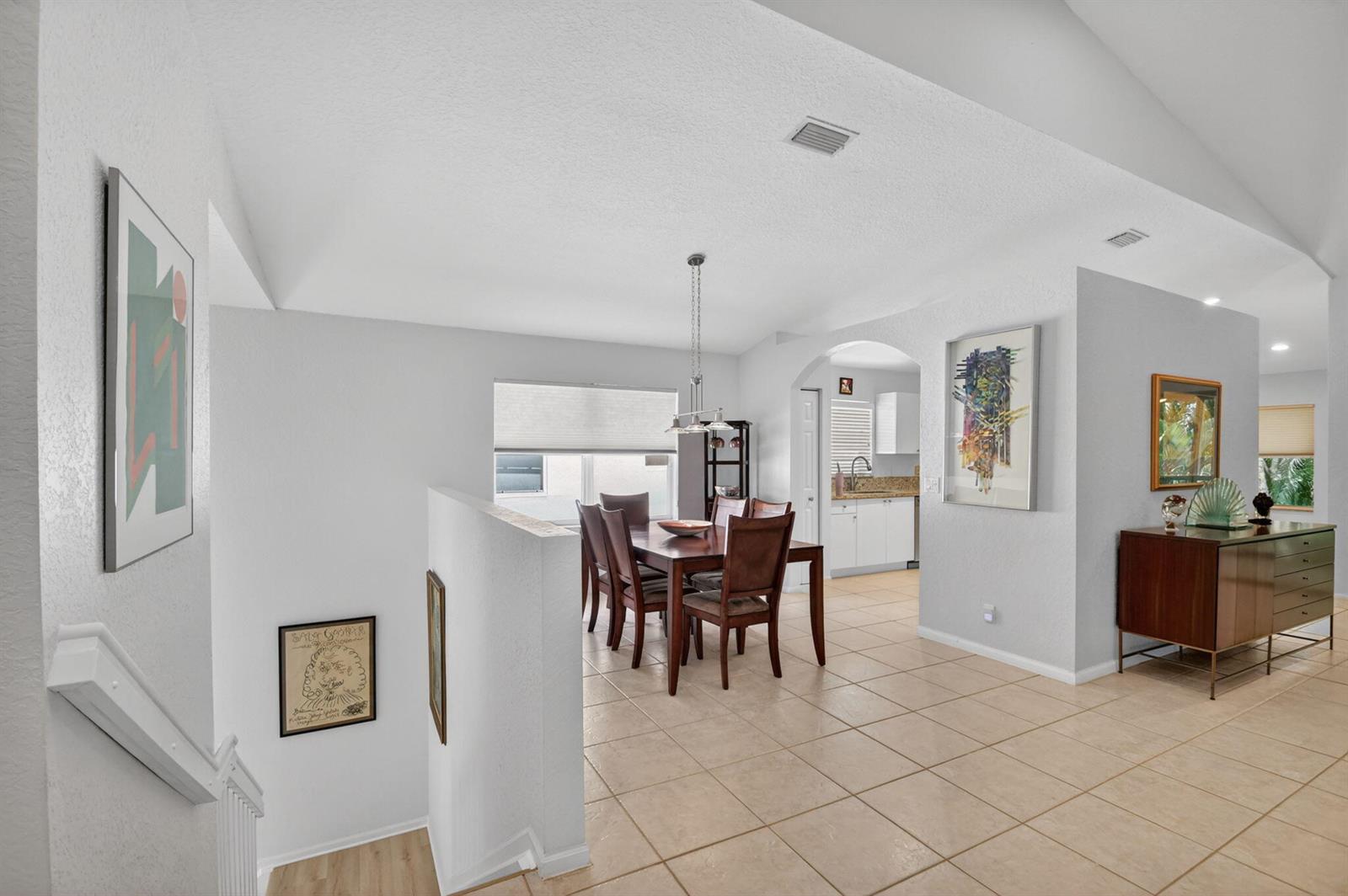 A dining area with a wooden table and chairs sits near a staircase and kitchen — 7910 Laina Lane # 3, Boynton Beach FL 33437, BOYNTON BEACH, FL