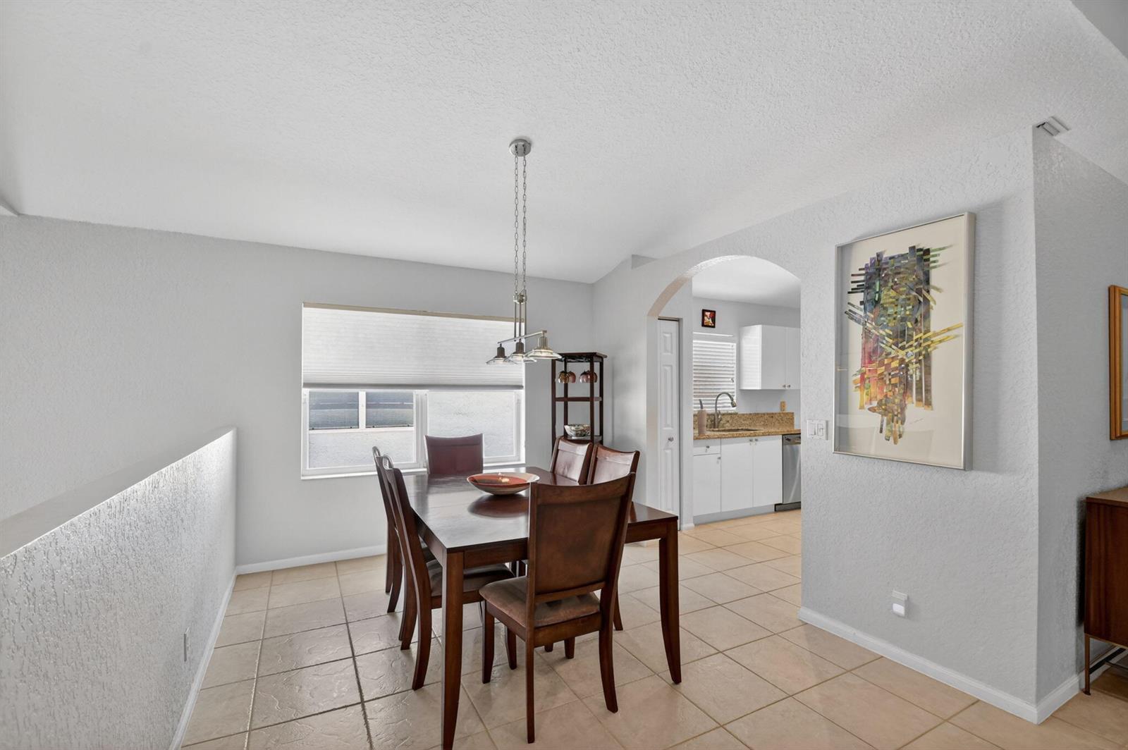 A dining room with a wooden table and chairs sits next to an arched kitchen entrance — 7910 Laina Lane # 3, Boynton Beach FL 33437, BOYNTON BEACH, FL
