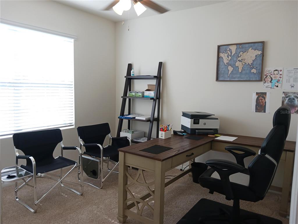 A home office features a wooden desk, an ergonomic chair, two folding chairs, and shelving — 563 HONEY BELL ROAD, WINTER HAVEN, FL