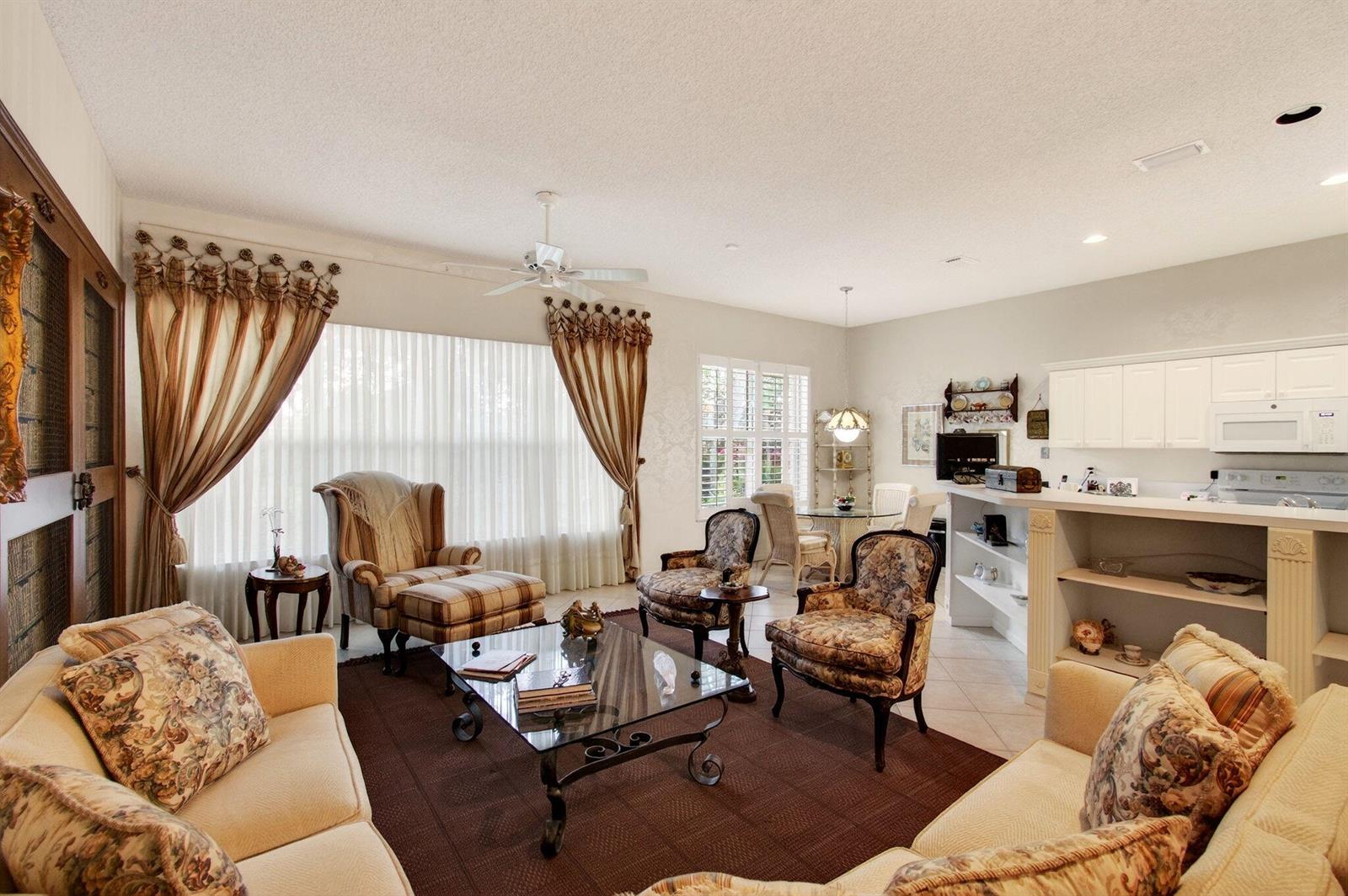A living room with a brown rug, patterned armchairs, and a kitchen counter area — 7844 Rockford Road, Boynton Beach FL 33472, BOYNTON BEACH, FL