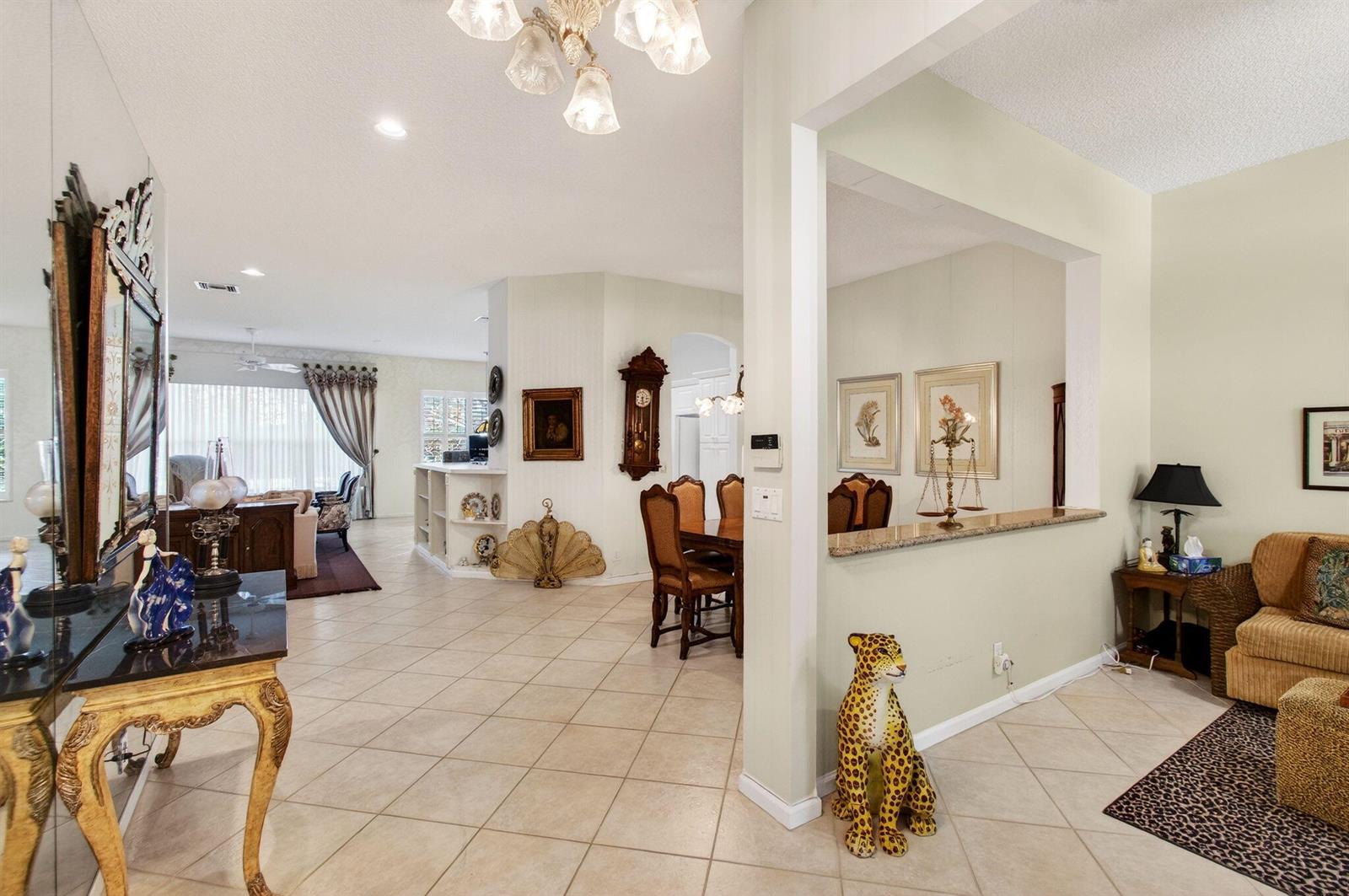 An open-concept living area features tiled floors, a dining space, and a decorative leopard statue — 7844 Rockford Road, Boynton Beach FL 33472, BOYNTON BEACH, FL
