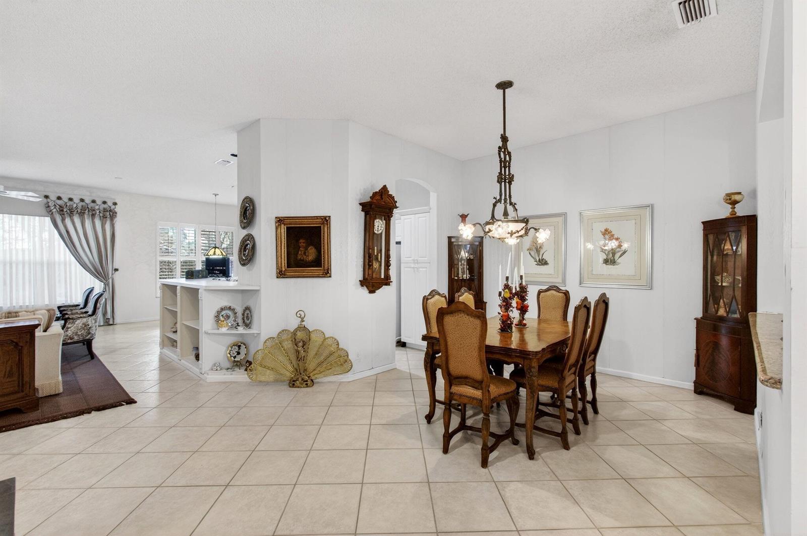 A dining area with a wooden table and chairs sits adjacent to a living room — 7844 Rockford Road, Boynton Beach FL 33472, BOYNTON BEACH, FL