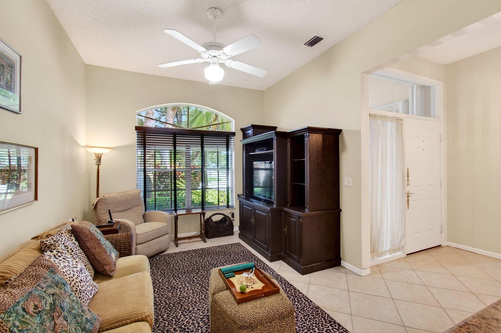 A living room with a beige sofa, dark wood entertainment center, and a patterned area rug — 7844 Rockford Road, Boynton Beach FL 33472, BOYNTON BEACH, FL