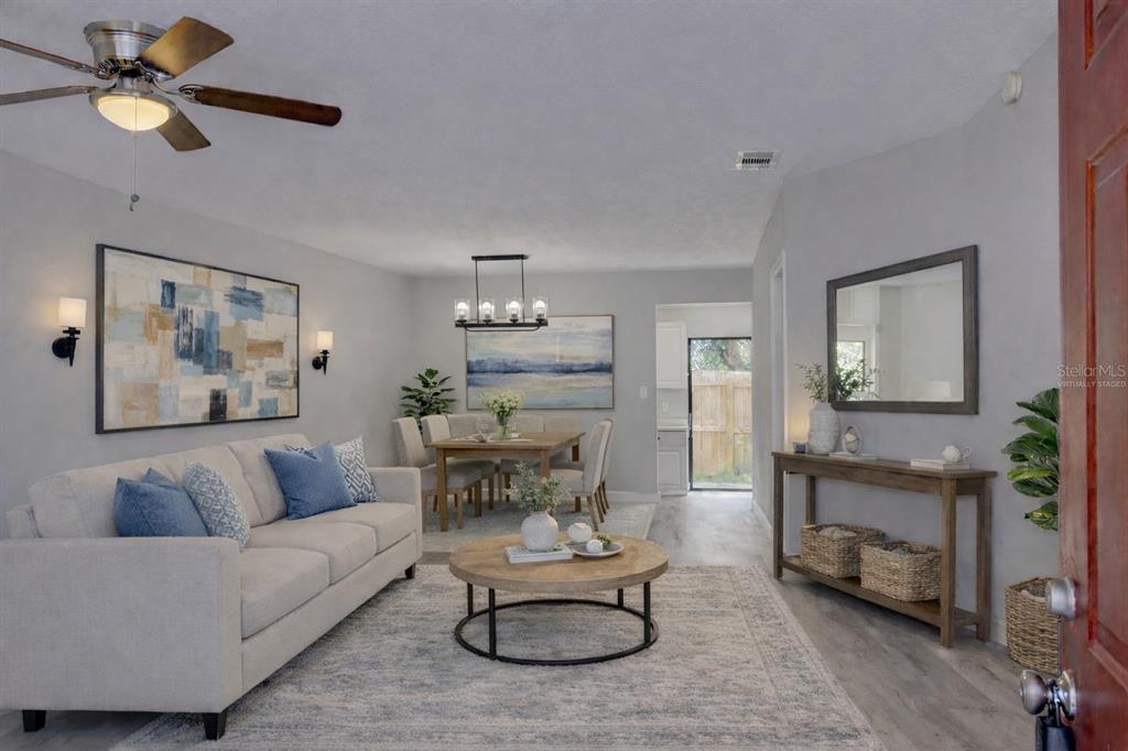 A living room and dining area with light gray walls, wood-look flooring, and neutral furniture — 6296 RIVER RUN PLACE UNIT 194, ORLANDO, FL