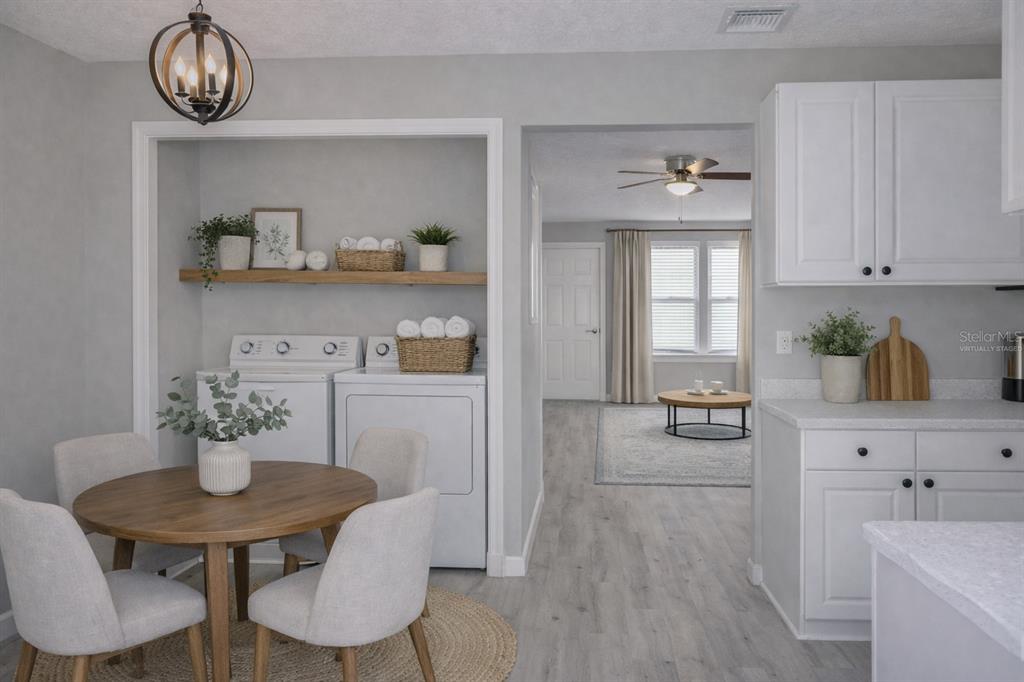 A dining area with a round table and laundry appliances in a recessed wall niche — 6296 RIVER RUN PLACE UNIT 194, ORLANDO, FL