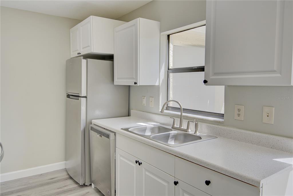 A kitchen features white cabinets, stainless steel appliances, a double sink, and light countertops — 6296 RIVER RUN PLACE UNIT 194, ORLANDO, FL
