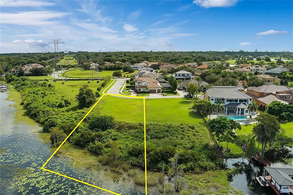 An aerial view shows a vacant waterfront lot outlined in yellow next to residential homes — 5727 EMERINGTON CRESCENT, ORLANDO, FL