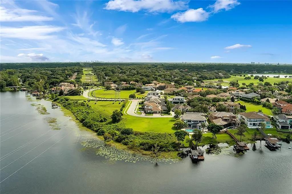 An aerial view of a residential neighborhood situated along a lake with a grassy lawn — 5727 EMERINGTON CRESCENT, ORLANDO, FL