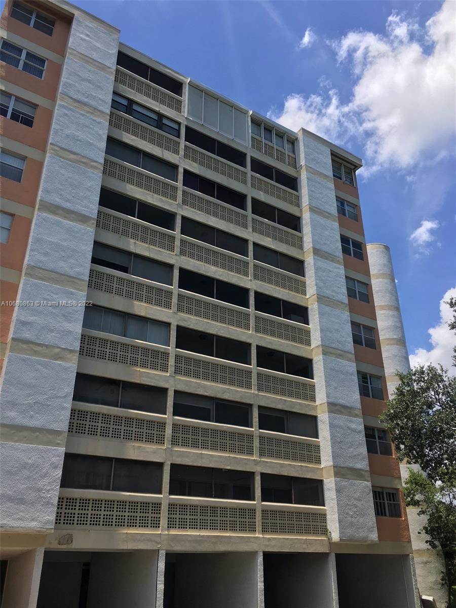A low-angle view of a multi-story residential building with screened balconies and textured exterior walls — 3301 Spanish Moss Ter # 906, Lauderhill FL 33319, LAUDERHILL, FL