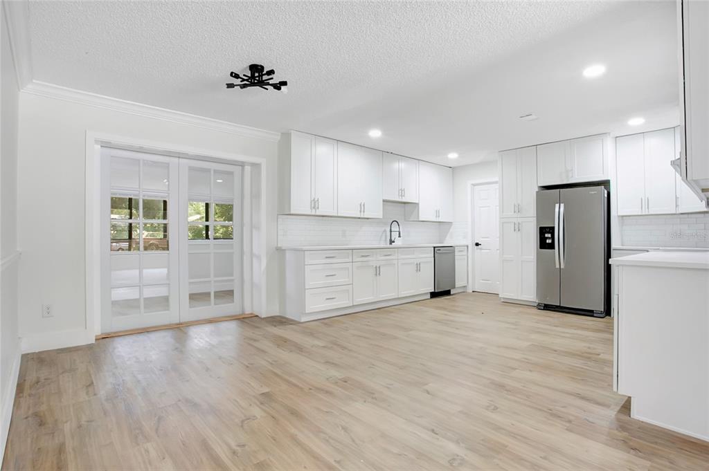A bright kitchen features white cabinets, stainless steel appliances, and light wood-look flooring — 1221 FOREST CIRCLE, ALTAMONTE SPRINGS, FL