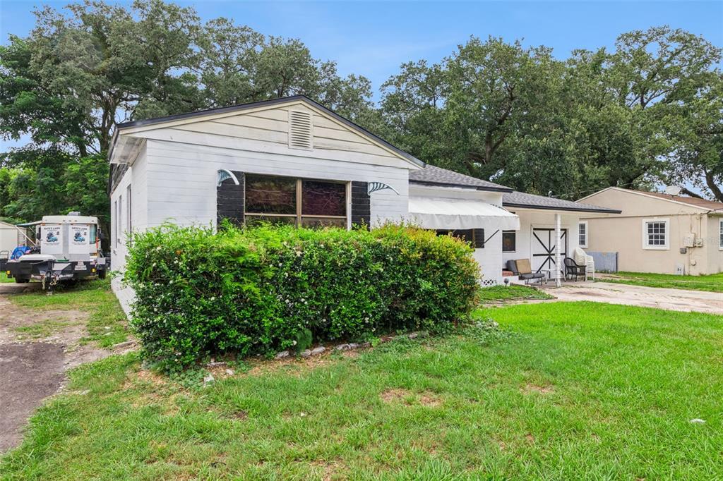 A white, single-story house with a large hedge, a carport, and a trailer parked nearby — 1411 35TH STREET, ORLANDO, FL