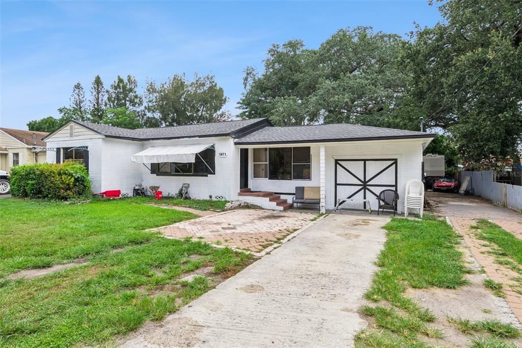 A single-story white brick house features a concrete driveway, a paved patio, and a garage — 1411 35TH STREET, ORLANDO, FL