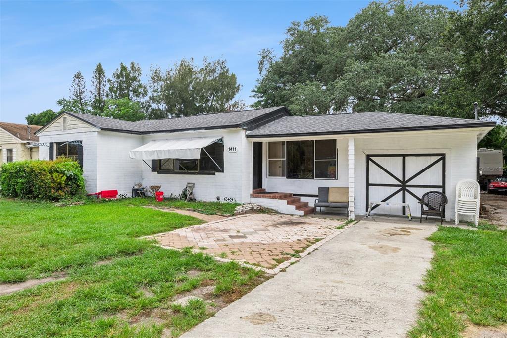 A single-story white brick house with a paved driveway, front patio, and a garage door — 1411 35TH STREET, ORLANDO, FL
