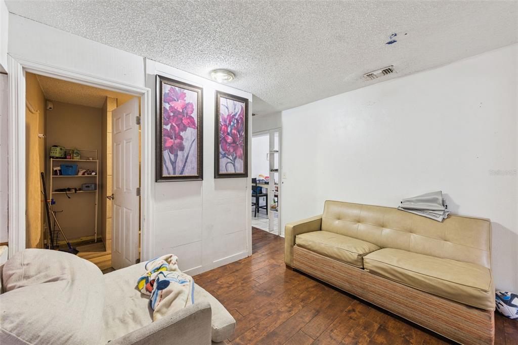 A living room features wood-look flooring, a beige sofa, and two floral wall art pieces — 1411 35TH STREET, ORLANDO, FL