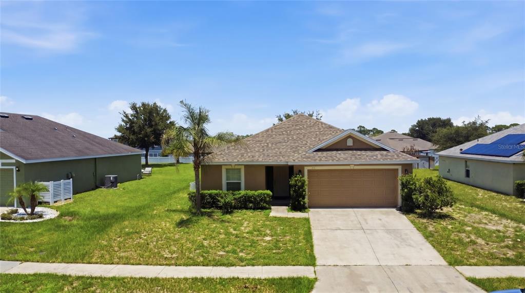 A single-story suburban house with a tan exterior, a two-car garage, and a palm tree — 184 ELEUTHERA DRIVE, LAKE ALFRED, FL