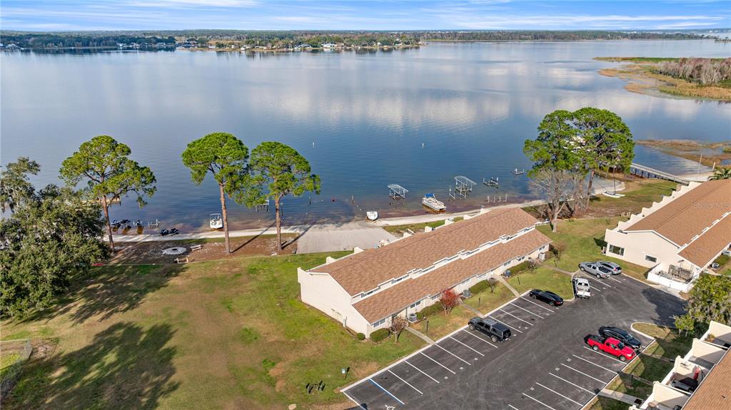 An aerial view shows a waterfront townhouse complex with a parking lot and boat docks — 11001 SE SUNSET HARBOR ROAD UNIT B14, SUMMERFIELD, FL