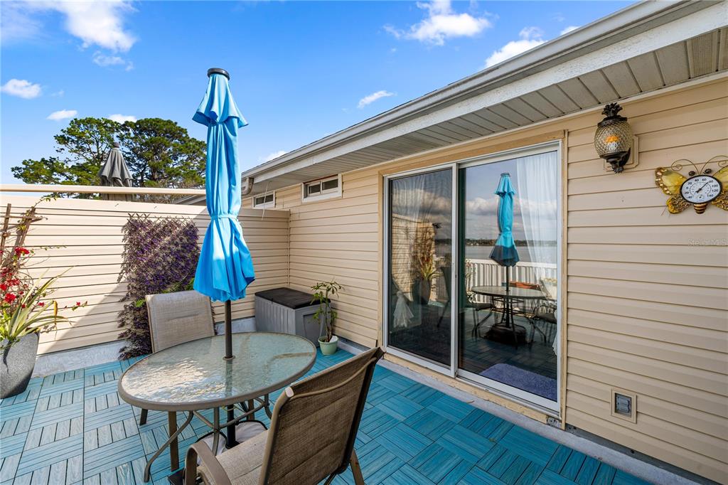 A patio with blue interlocking tiles, a glass table, chairs, and a sliding glass door — 11001 SE SUNSET HARBOR ROAD UNIT B14, SUMMERFIELD, FL