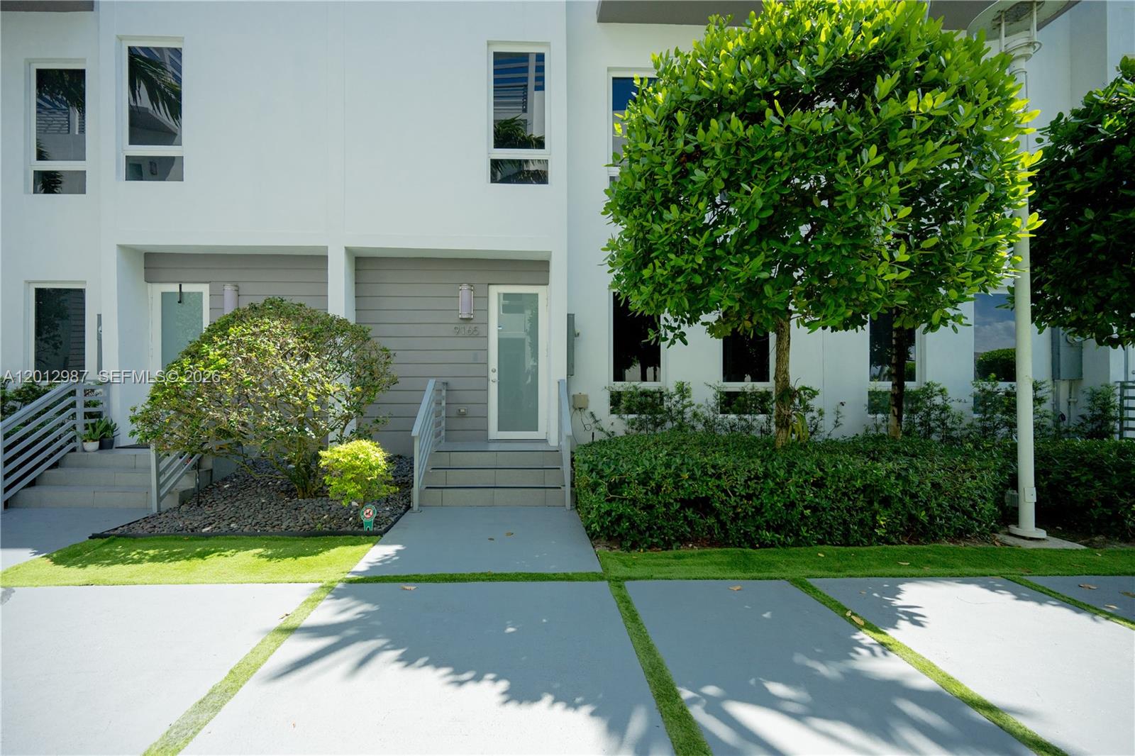 A modern white townhouse exterior features a gray front door, concrete steps, and landscaping — 9165 NW 33rd St, Doral FL 33172, DORAL, FL