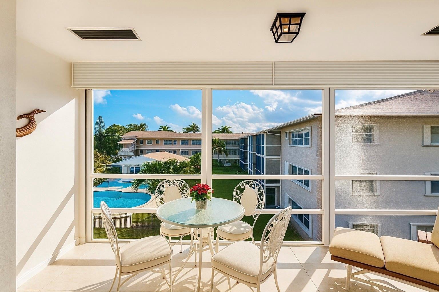 A sunroom with a dining set overlooks a swimming pool and neighboring apartment buildings — 700 Layne Boulevard # 301, Hallandale Beach FL 33009, HALLANDALE BEACH, FL