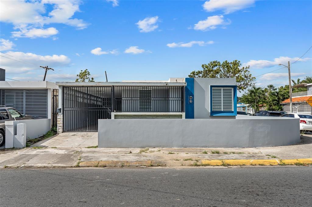 A single-story house with a gray concrete wall, a carport, and a blue-trimmed window — 1210 CALLE MARIA BUSTAMANTE, SAN JUAN, PR