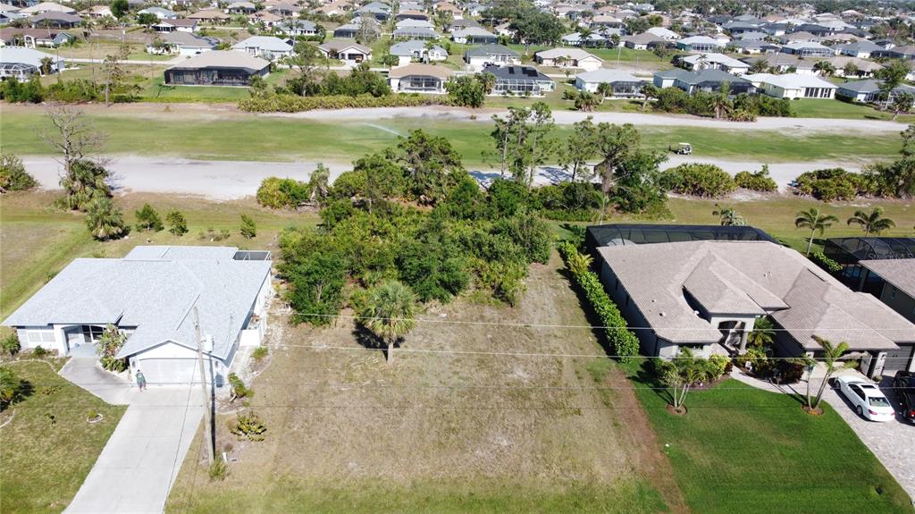 An aerial view shows a vacant residential lot situated between two existing houses — 74 PINEHURST PLACE, ROTONDA WEST, FL