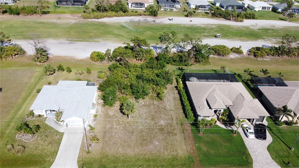 An aerial view shows a vacant residential lot situated between two houses near a golf course — 74 PINEHURST PLACE, ROTONDA WEST, FL