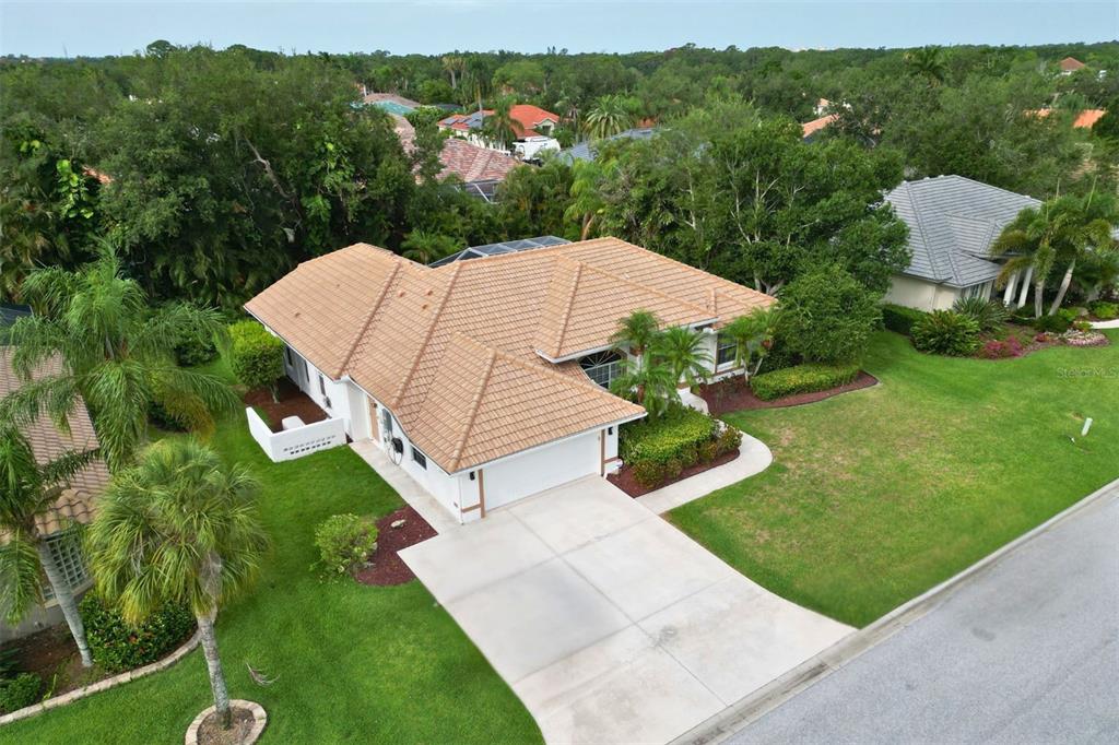 An aerial view shows a single-story house with a tiled roof and a concrete driveway — 4824 HANGING MOSS LANE, SARASOTA, FL