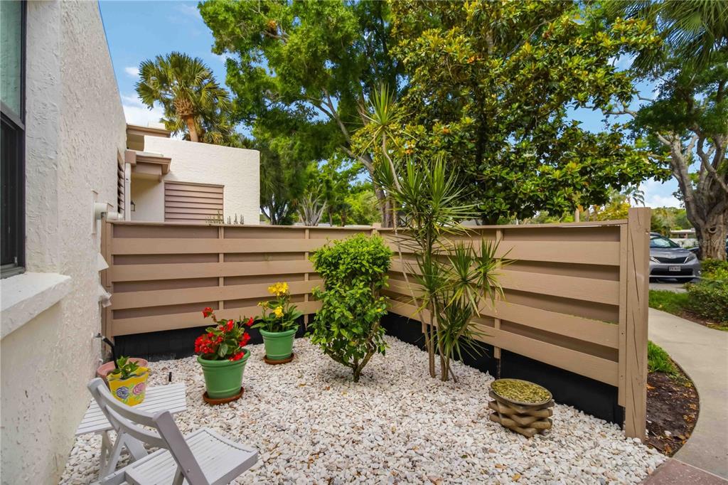 A small patio area features a green door, white gravel, a chair, and potted plants — 149 PINEHURST DRIVE UNIT 149, BRADENTON, FL