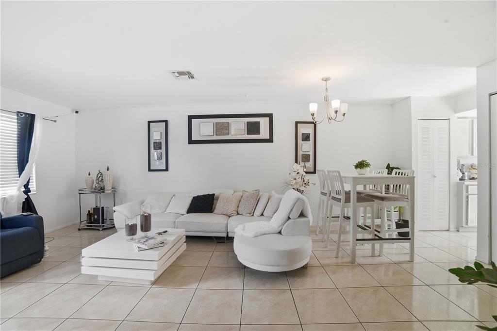 A bright living and dining area features white tile floors, a sectional sofa, and furniture — 2 E LAS PALMAS WAY, KISSIMMEE, FL