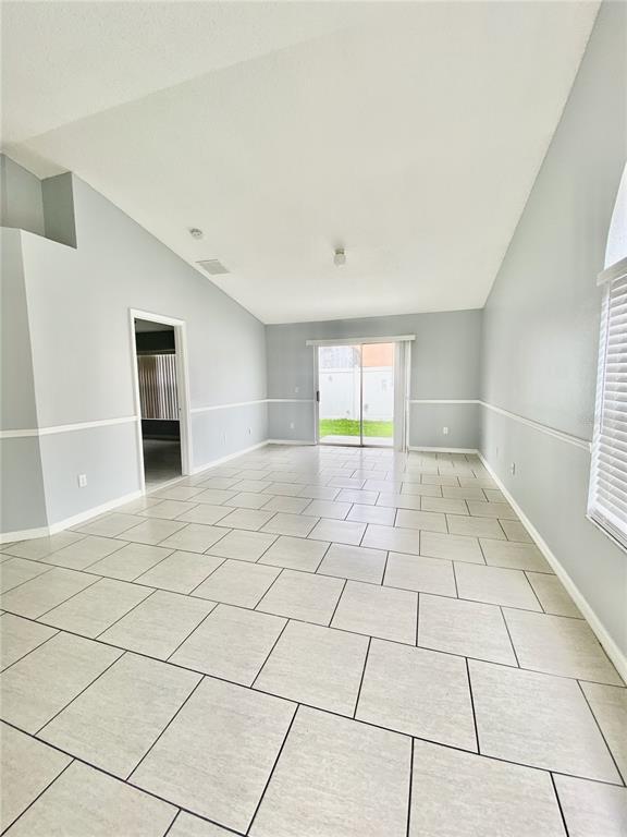 A bright living room features light gray walls, white chair rail molding, and tiled flooring — 2298 SANTA LUCIA STREET, KISSIMMEE, FL