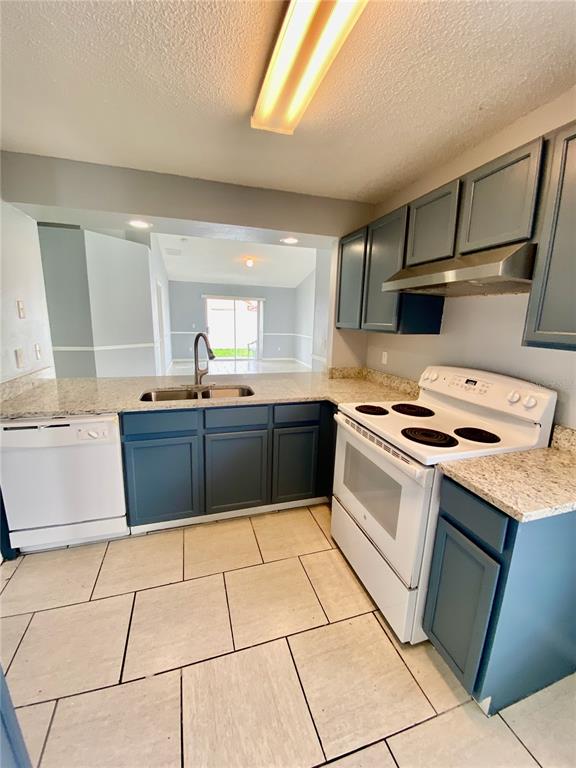 A kitchen features blue cabinets, granite countertops, white appliances, and light-colored tile flooring — 2298 SANTA LUCIA STREET, KISSIMMEE, FL