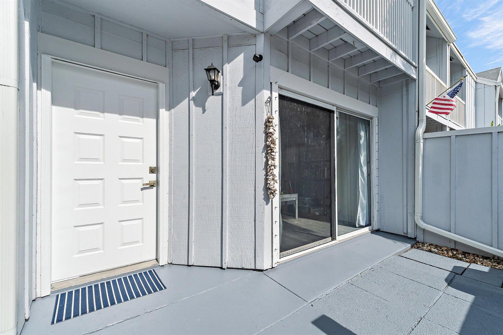 A white front door and sliding glass door open onto a gray concrete patio area — 6343 Riverwalk Lane # 3, Jupiter FL 33458, JUPITER, FL