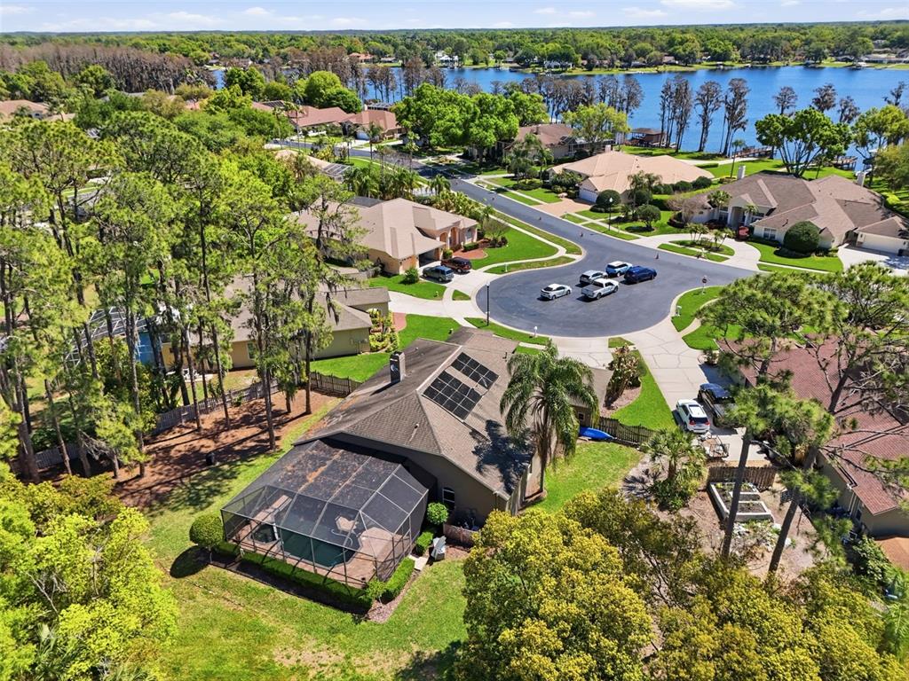 An aerial view shows several waterfront homes with private docks along a lake — 3629 WHISTLING LANE, LAND O LAKES, FL