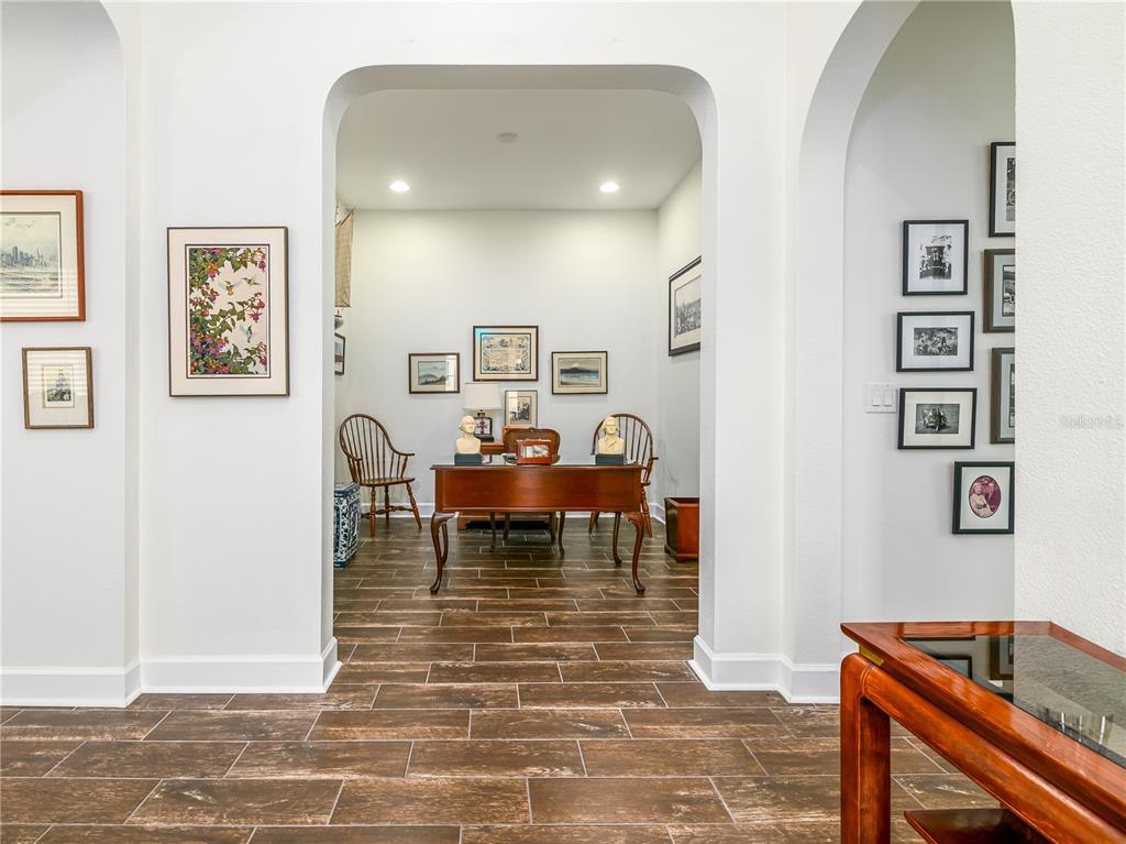 A view through an arched doorway into a home office with wood-look tile flooring — 4521 BARLETTA COURT, WESLEY CHAPEL, FL